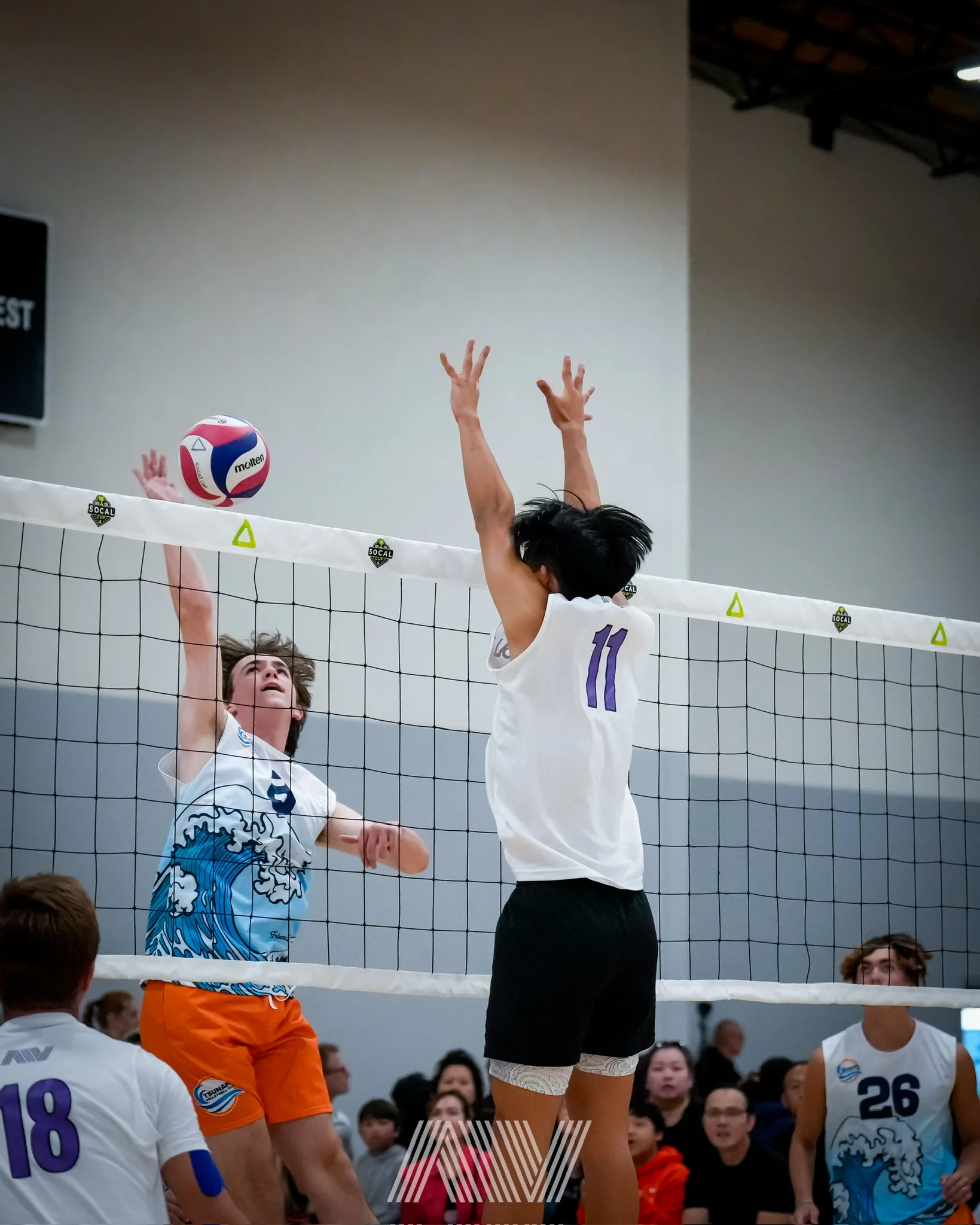 A4 boys volleyball attacker hitting over a block