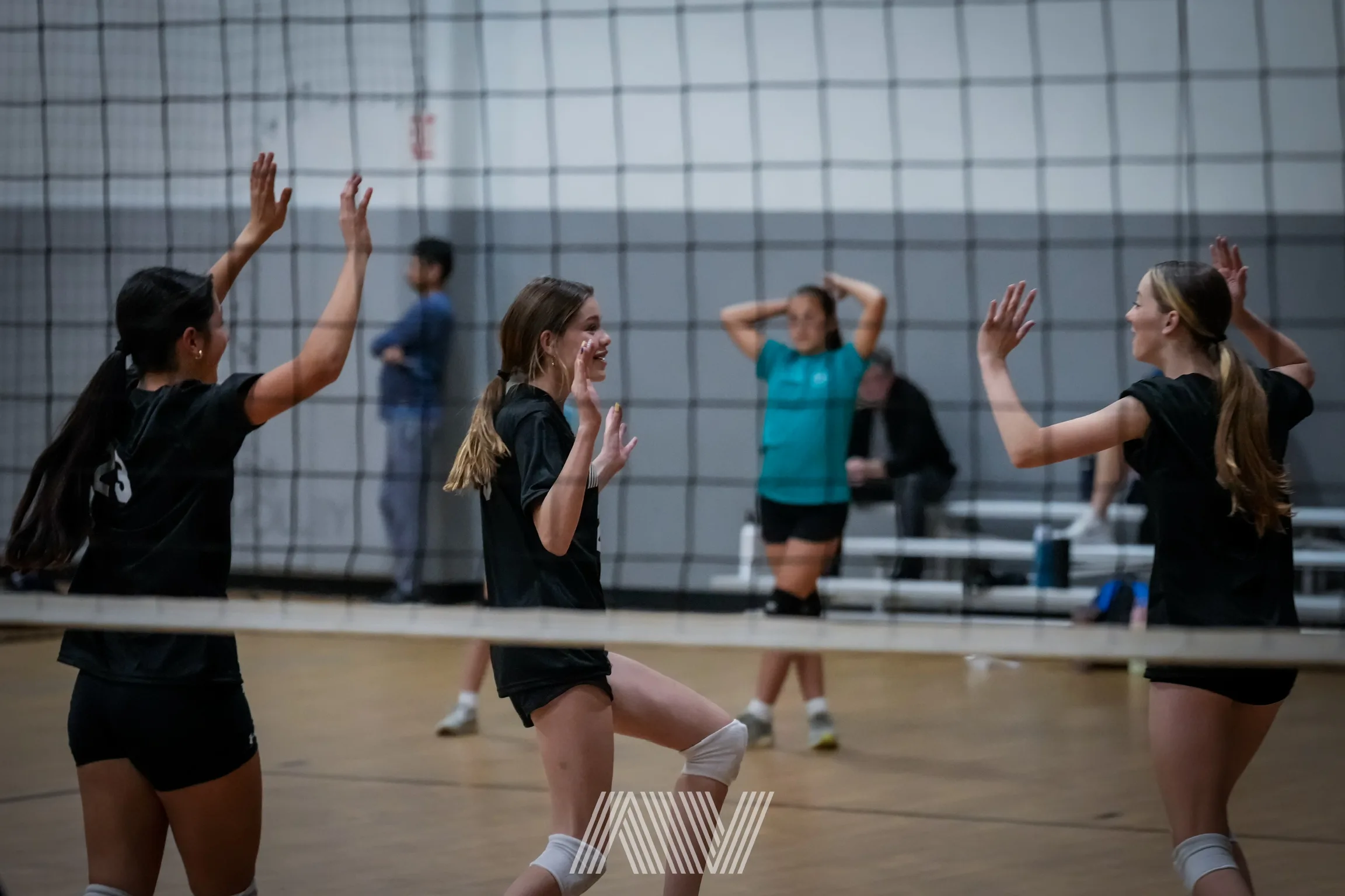 A4 girls volleyball athletes celebrating at the net